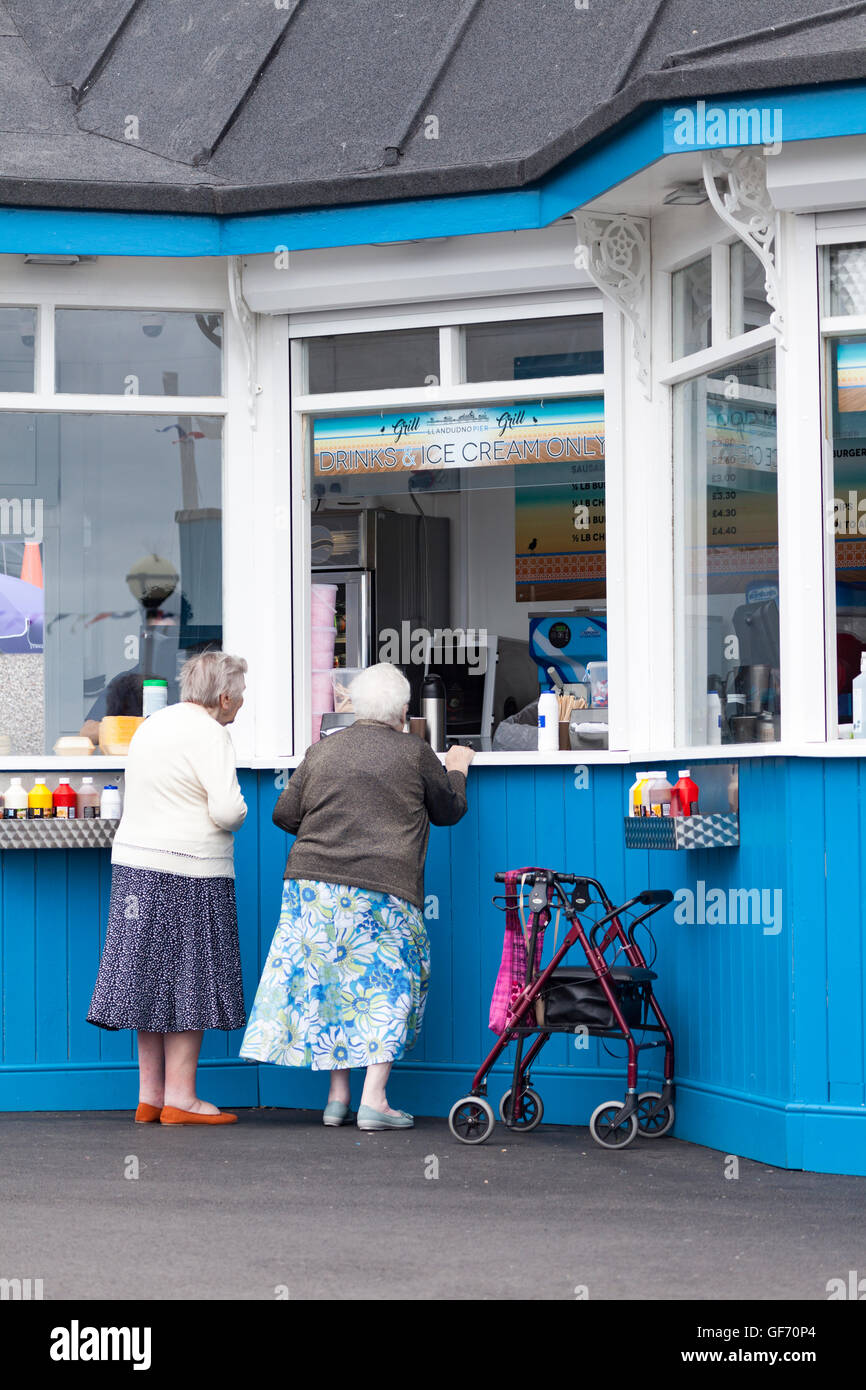 Ältere Damen Kauf von Lebensmitteln an einem Kiosk auf Llandudno Pier in dem Urlaubsort an der Küste von North Wales, UK Stockfoto