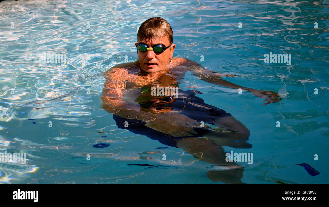 Mann mit Brille in einem Schwimmbad an einem sonnigen Tag. Stockfoto