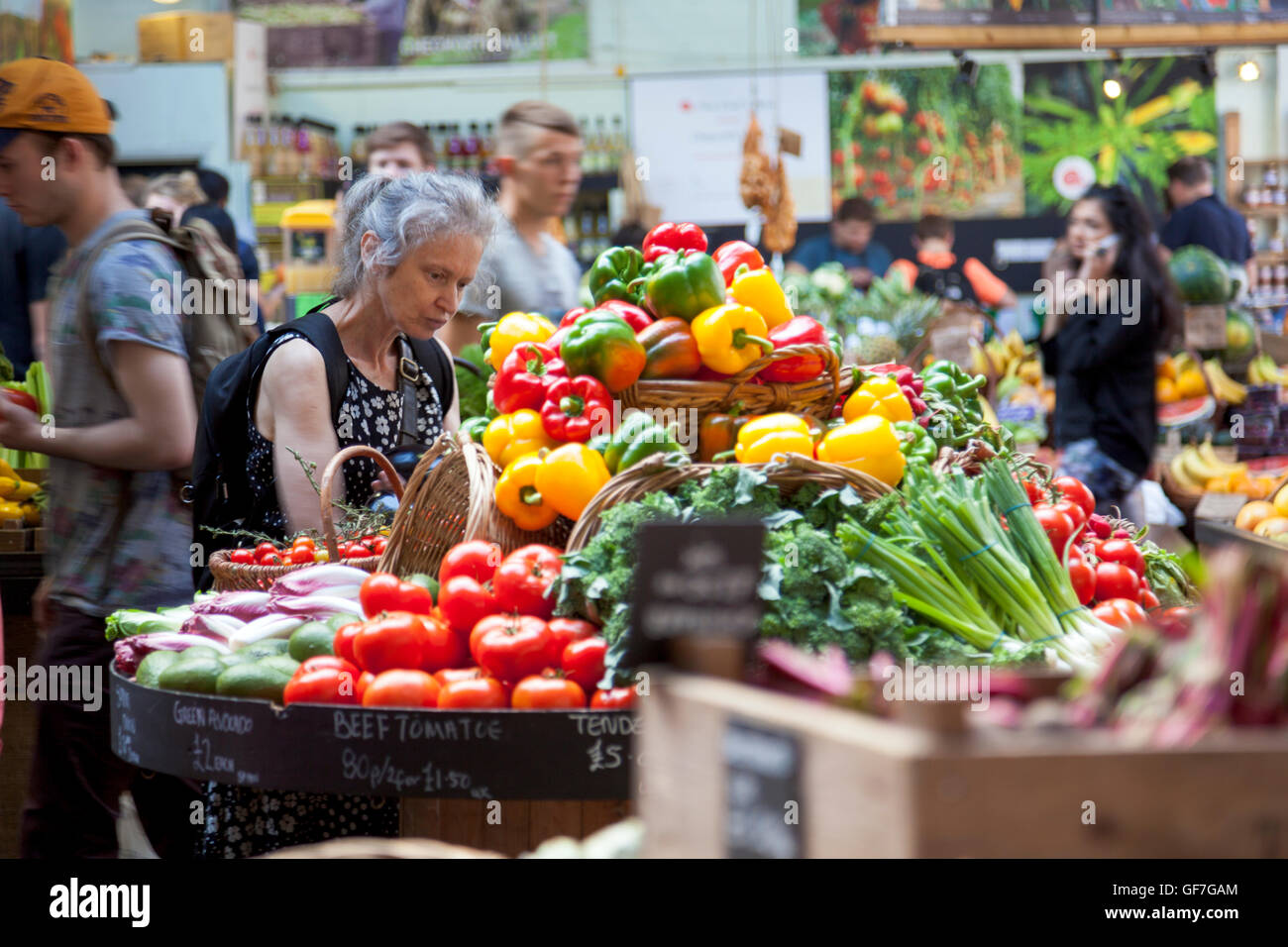 Eine ältere Dame, die Auswahl von Gemüse auf einem Markt (Borough Market, London, UK) Stockfoto