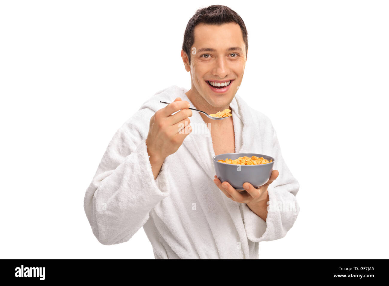 Lächelnde junge Mann isst Müsli aus einer Schüssel isoliert auf weißem Hintergrund Stockfoto