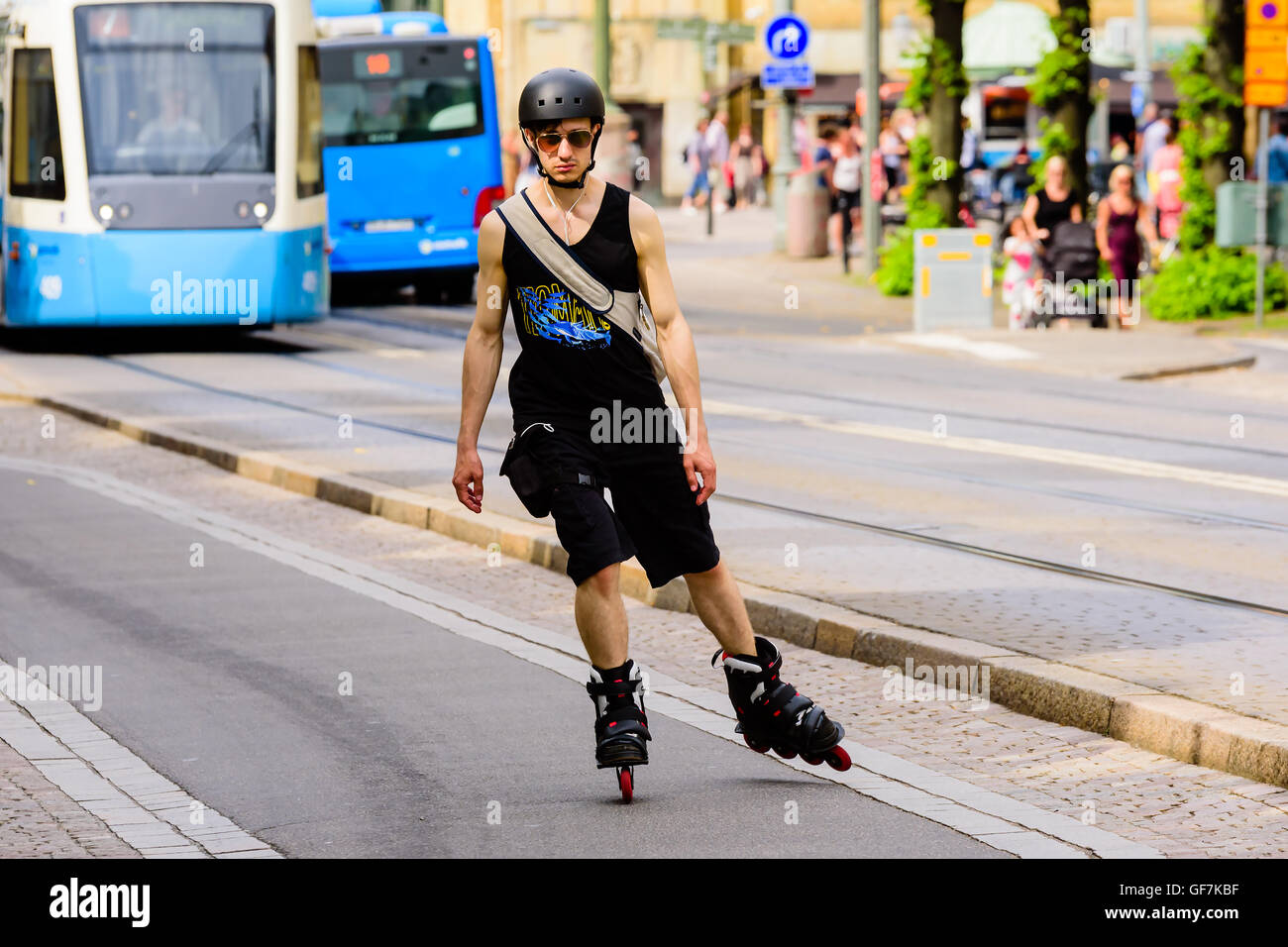 Göteborg, Schweden - 25. Juli 2016: Junge erwachsene Mann Skaten in Richtung Sie mit Straßenbahnen im Hintergrund. Echte Menschen in everyd Stockfoto