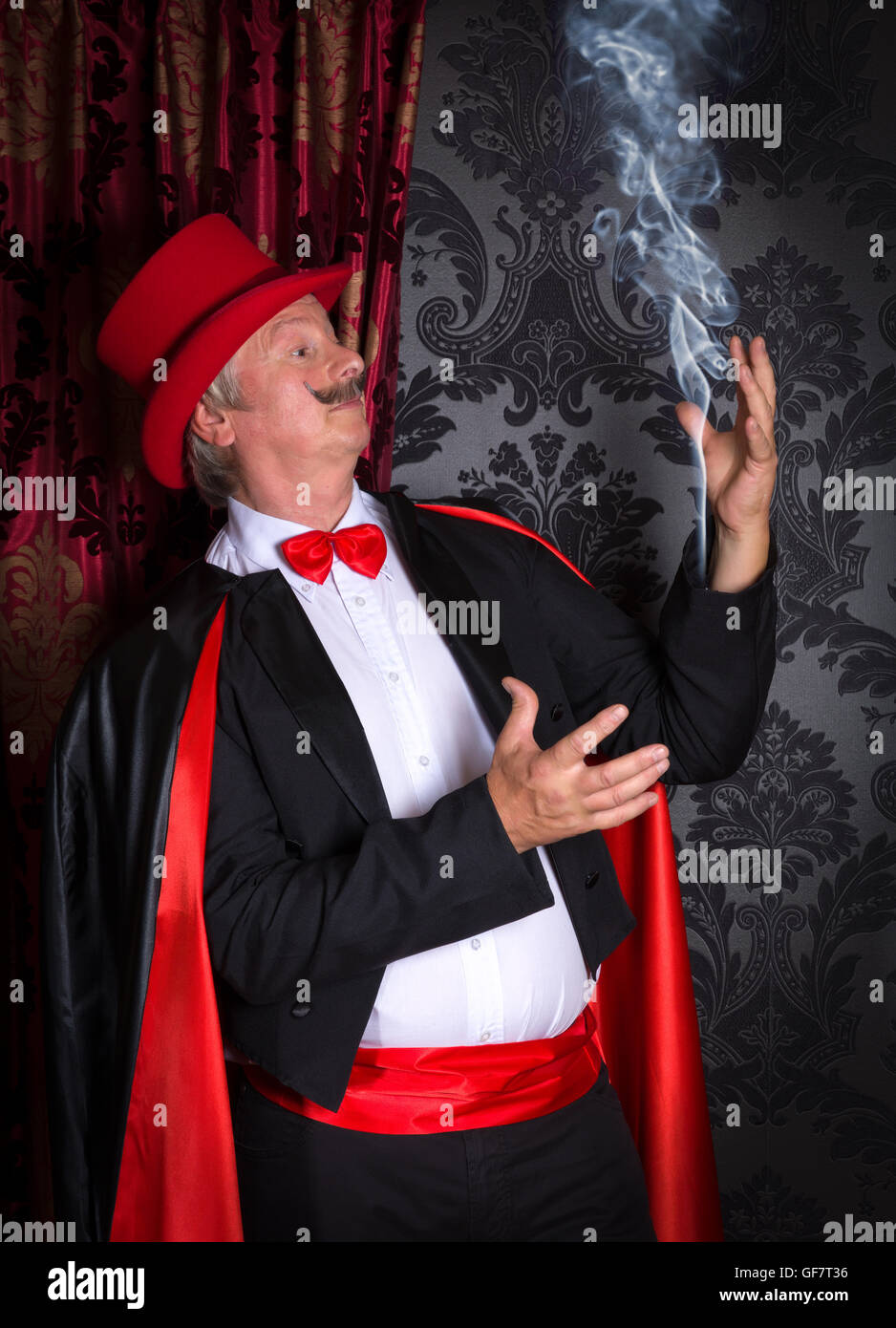 Lustige Zauberer machen Rauch aus seinem Smoking-Hülse Stockfoto