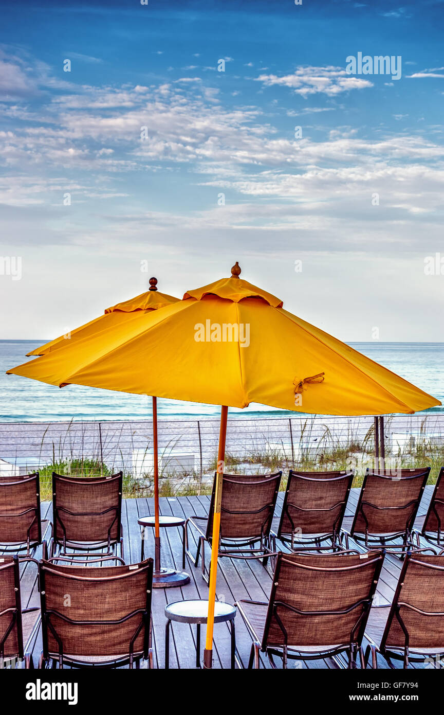 Stühle, Tische und Regenschirm auf einem Holzsteg am Strand von Destin, FL Stockfoto