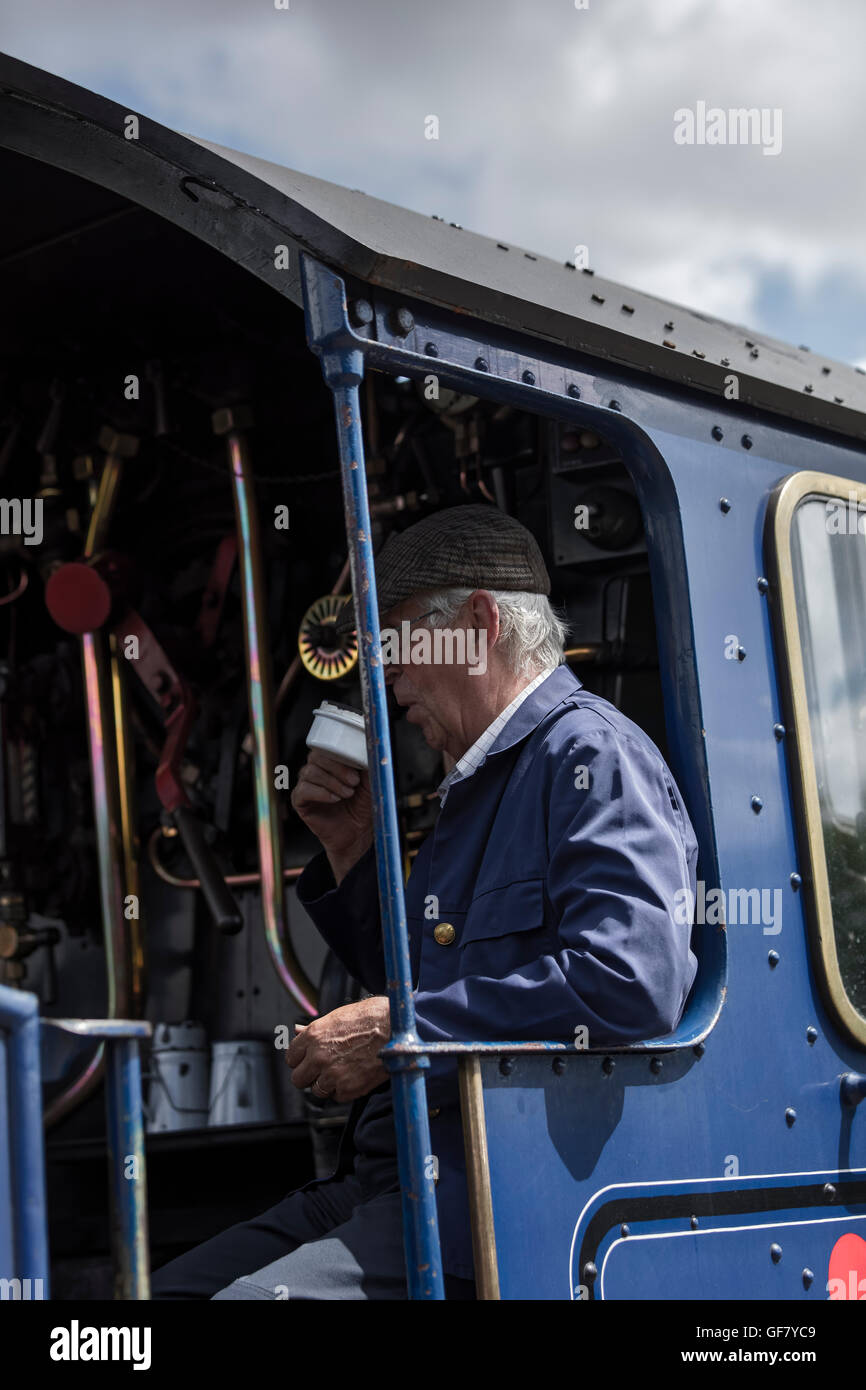 Zug-Crew-Mitglied in der Kabine der restaurierten Dampflokomotive König Edward II, trinken eine Tasse Tee am Bahnhof Stockfoto