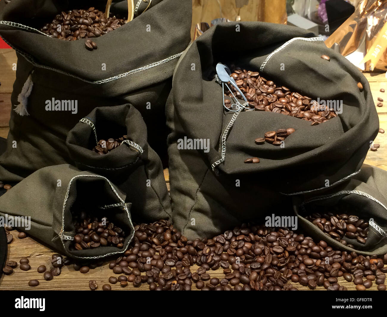 Kaffeebohnen auf Taschen über rustikale Holz Hintergrund Stockfoto