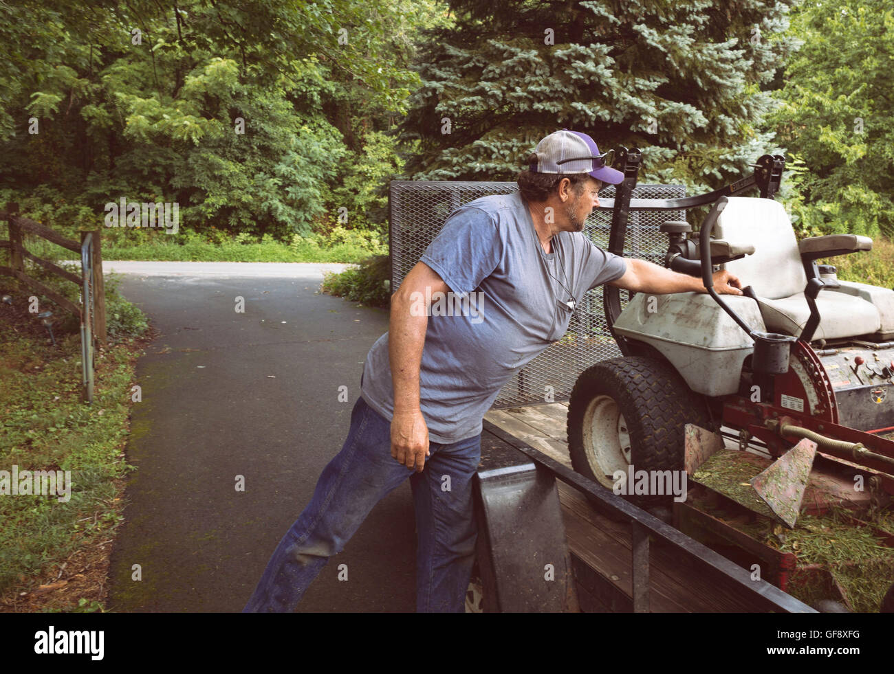 Mann laden Rasenmäher auf Anhänger auf Einfahrt in Virginia. Stockfoto