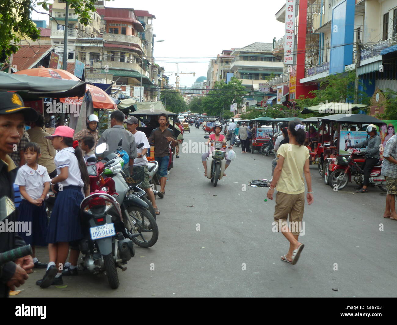 Straßenszene in Phnom Penh mit Menschen auf dem Weg zur Arbeit im Auto und Motorräder. Sehr lebhaften und pulsierenden kambodschanischen Stadt. Stockfoto