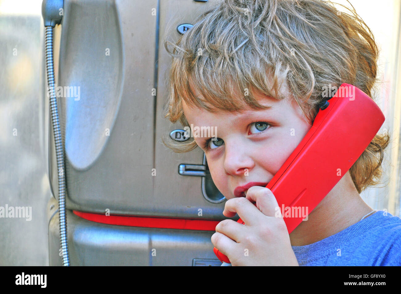 Kleines Kind durch öffentliches Telefon sprechen Stockfoto