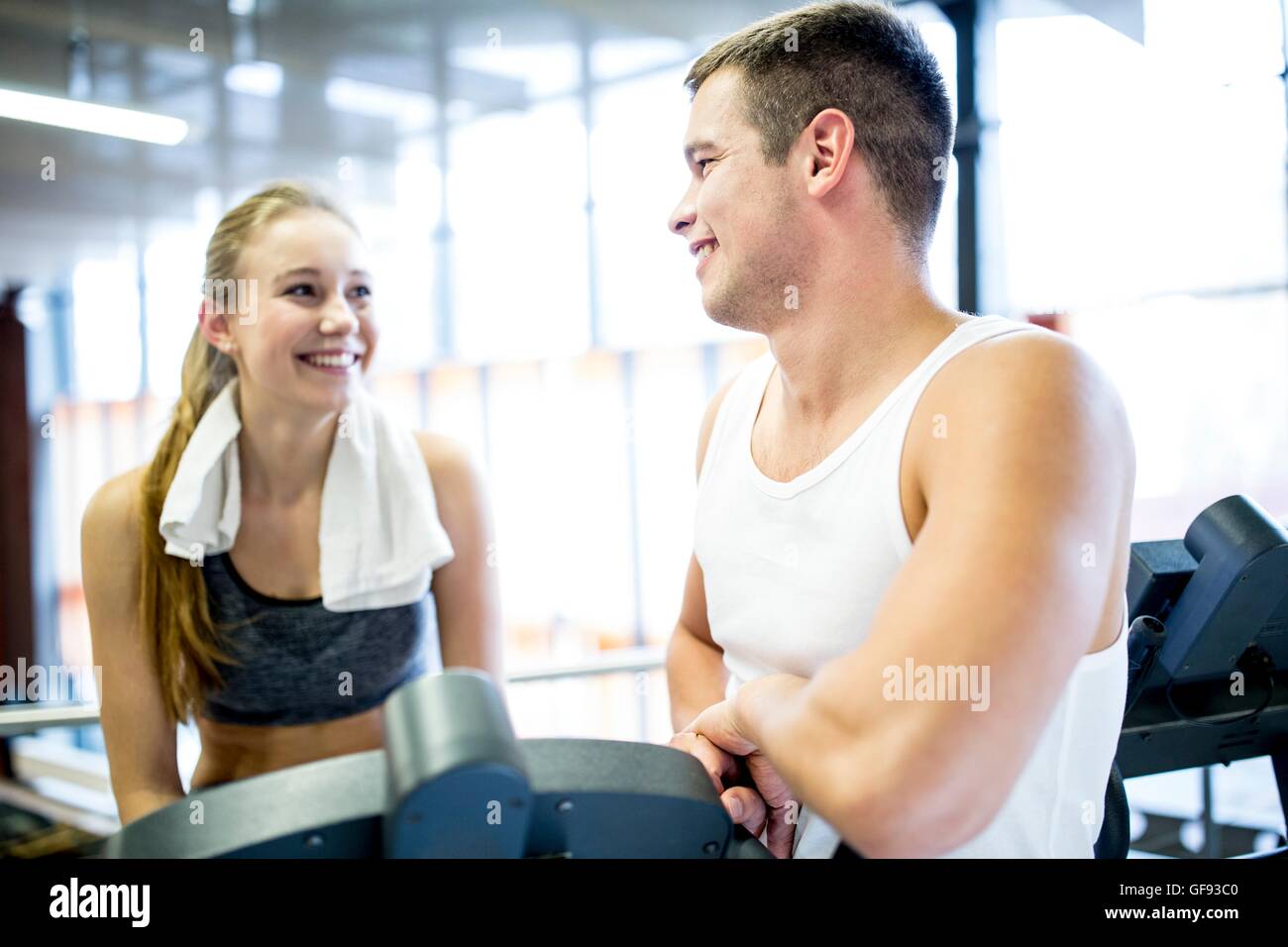 EIGENTUM FREIGEGEBEN. -MODELL VERÖFFENTLICHT. Junger Mann und Frau miteinander zu reden, während der Arbeit im Fitness-Studio, lächelnd. Stockfoto