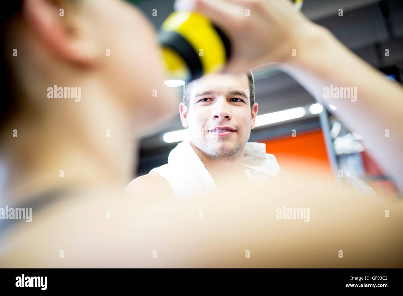 EIGENTUM FREIGEGEBEN. -MODELL VERÖFFENTLICHT. Mann sucht Frau beim Trinkwasser im Fitness-Studio. Stockfoto