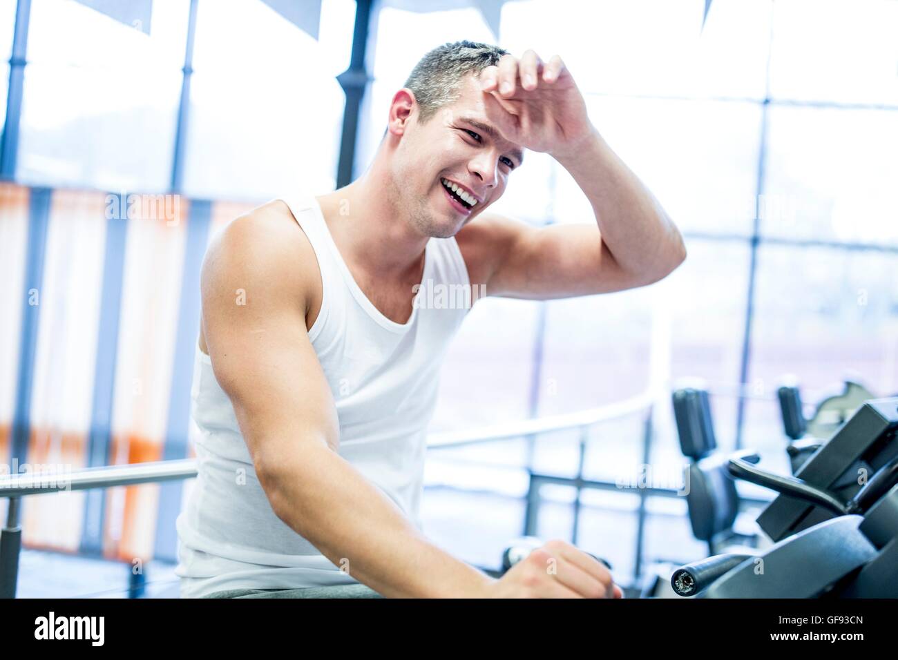 EIGENTUM FREIGEGEBEN. -MODELL VERÖFFENTLICHT. Junger Mann während des Trainings im Fitnessstudio schwitzen Lächeln auf den Lippen. Stockfoto
