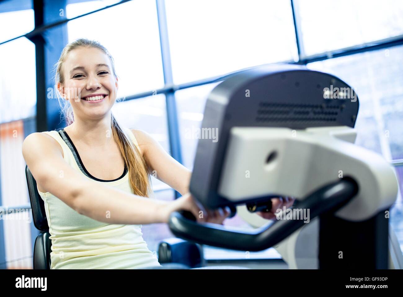 EIGENTUM FREIGEGEBEN. -MODELL VERÖFFENTLICHT. Porträt der jungen Frau auf Heimtrainer im Fitness-Studio trainieren. Stockfoto