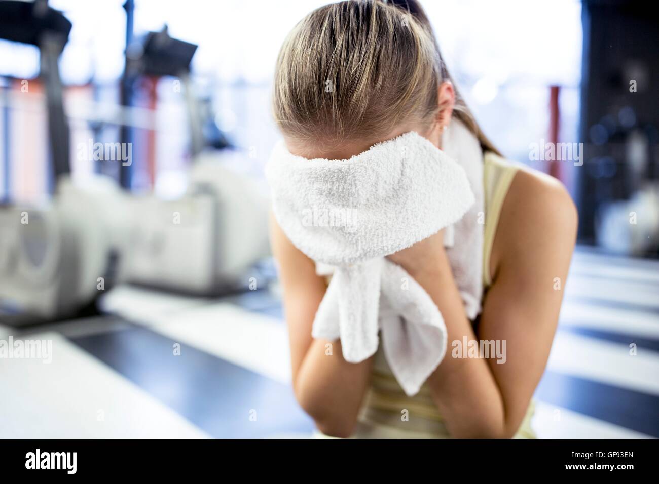 EIGENTUM FREIGEGEBEN. -MODELL VERÖFFENTLICHT. Junge Frau wischte sich den Schweiß mit Handtuch nach dem Training im Fitness-Studio. Stockfoto