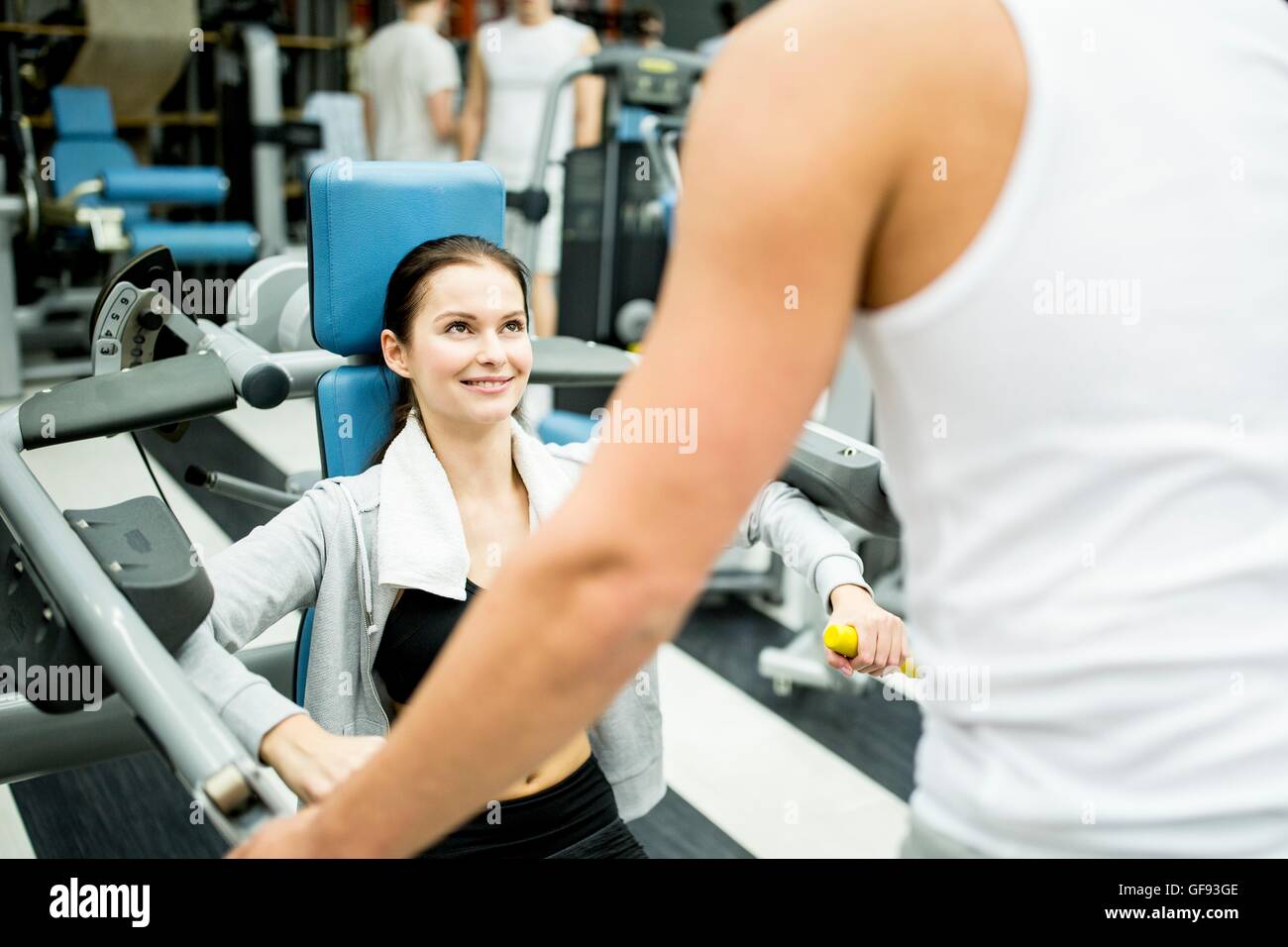 EIGENTUM FREIGEGEBEN. -MODELL VERÖFFENTLICHT. Junge Frau mit Trainer im Fitness-Studio trainieren. Stockfoto