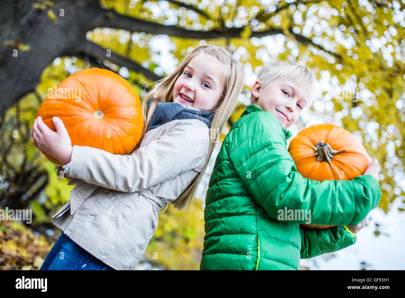-MODELL VERÖFFENTLICHT. Kinder mit Kürbis in Park, Porträt, Lächeln auf den Lippen. Stockfoto