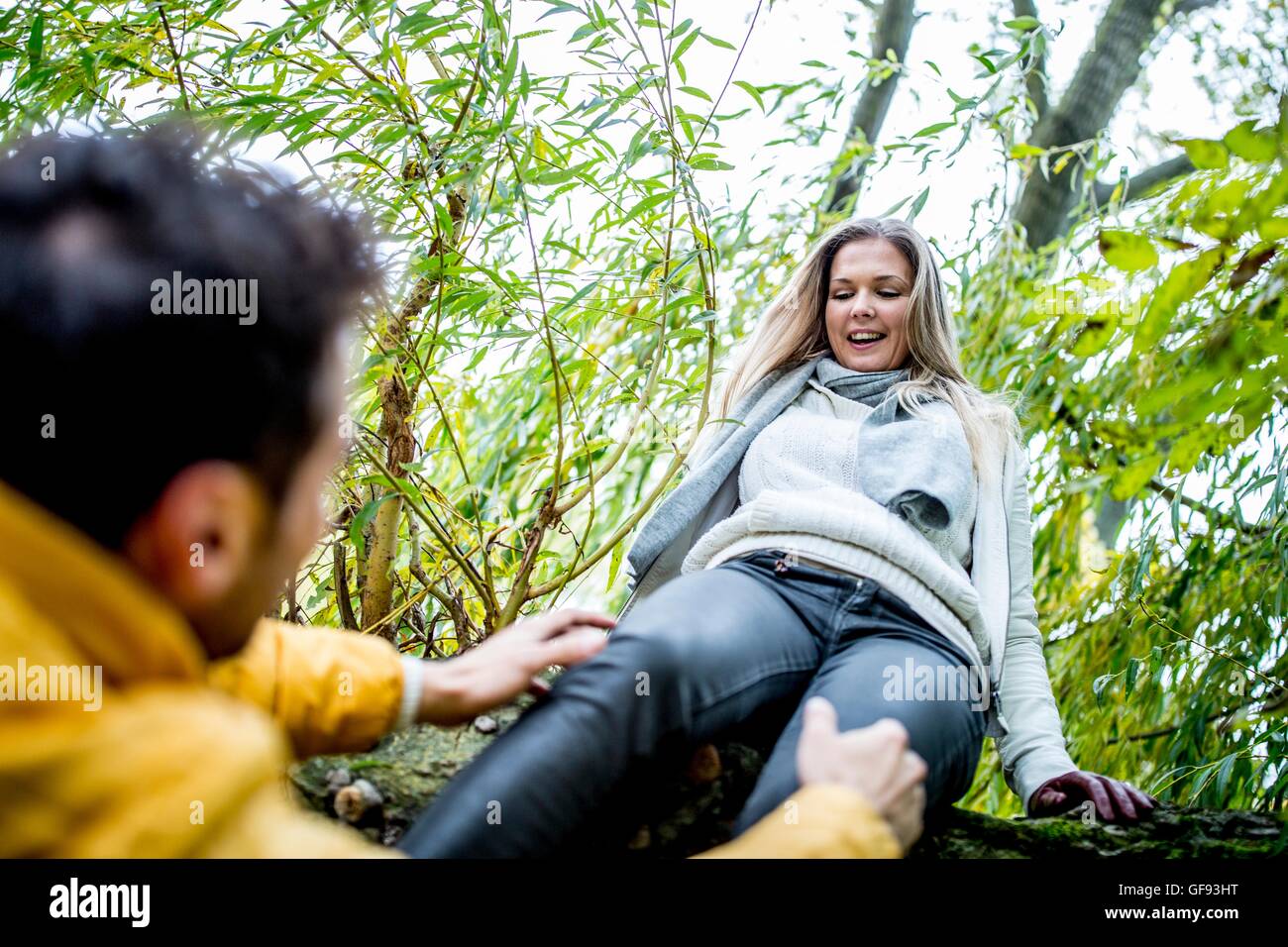 -MODELL VERÖFFENTLICHT. Junge Frau springt vom Baum während Mann unten stehen. Stockfoto