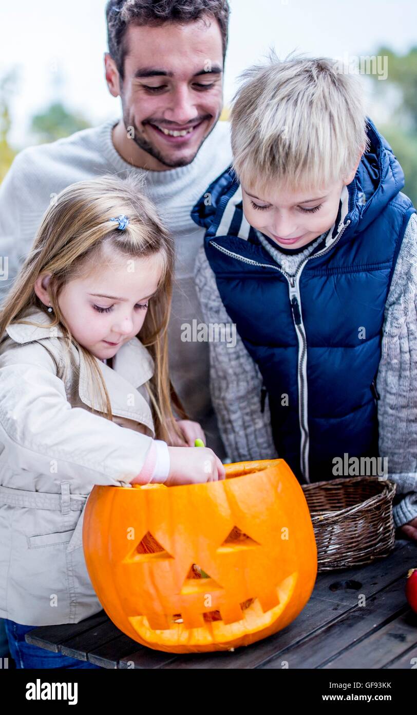 -MODELL VERÖFFENTLICHT. Vater und Kinder Halloween-Kürbis machen. Stockfoto