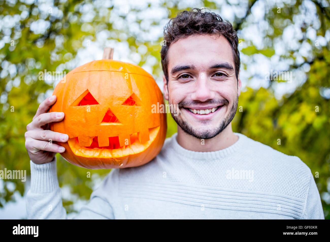 -MODELL VERÖFFENTLICHT. Porträt des jungen Mann, der Halloween-Kürbis hält. Stockfoto