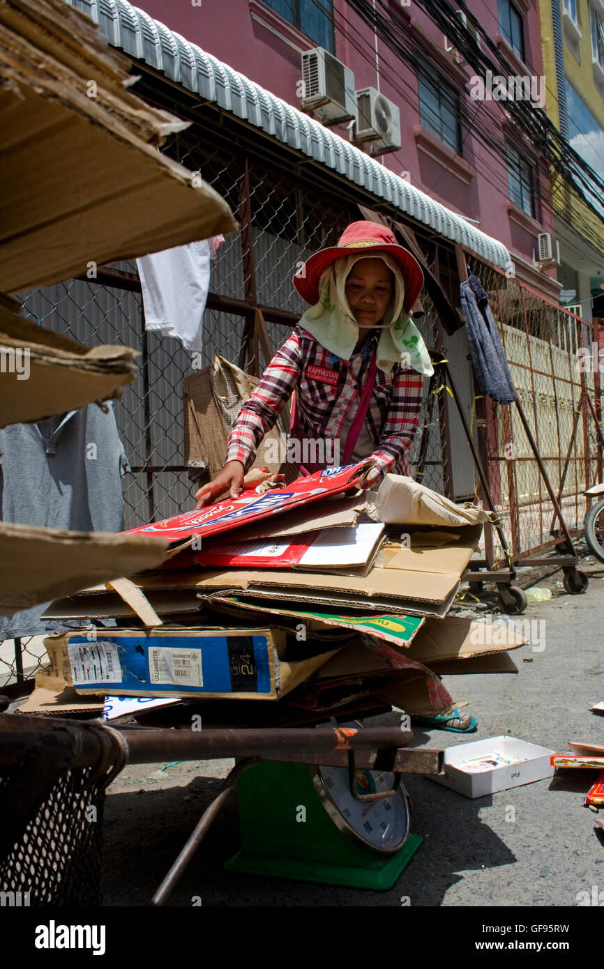 Eine Schnitzeljagd Frau wiegt Kartons auf einer Skala auf einer Stadtstraße in Phnom Penh, Kambodscha. Stockfoto