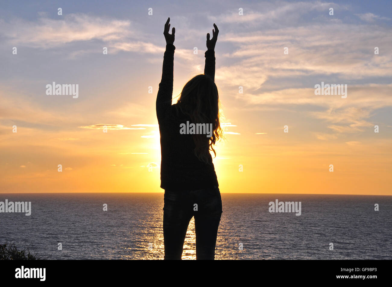 Silhouette eines Mädchens mit den Händen oben auf Sonnenuntergang Stockfoto
