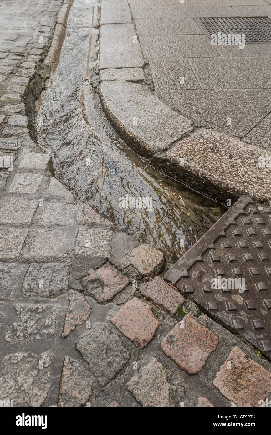 Straße Entwässerung/Rinne in Truro, Cornwall. Visuelle Metapher für "Geld in den Sand und Wasser/Abwasser. Stockfoto