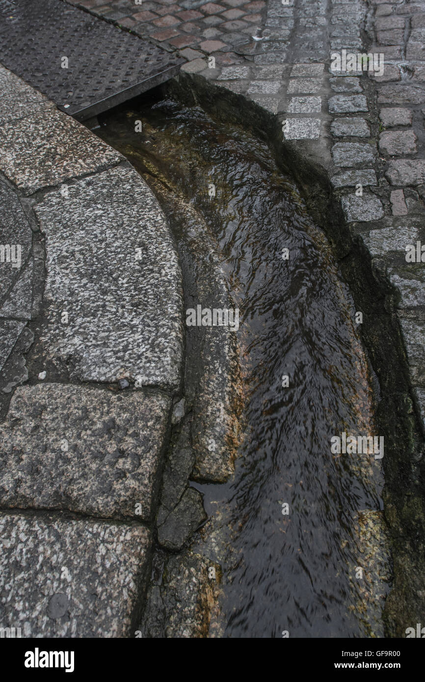 Straße Entwässerung/Rinne in Truro, Cornwall. Visuelle Metapher für "Geld in den Sand und Wasser/Abwasser. Stockfoto