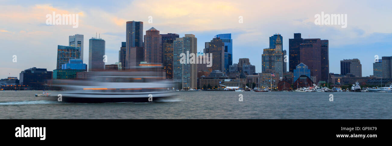 Ein Panorama-Foto einer unscharfen Fähre Reisen vorbei an der Skyline von Boston. Aufgenommen mit einer langen Belichtungszeit Bewegung zu zeigen. Stockfoto