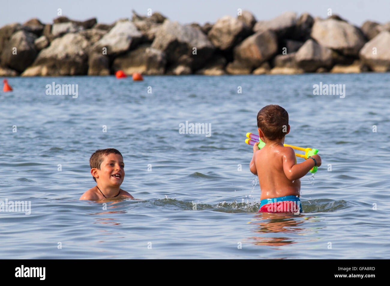 Glücklich Kinderspiel ins Meer mit Watergun, Urlaub in Italien-Cesenatico Stockfoto