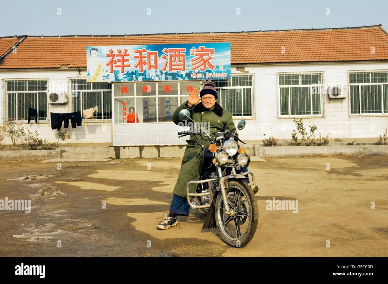 Mann auf dem Motorrad Motorrad am Straßenrand in der Nähe von Yantai Stadt in der Provinz Shandong, China. Winter Stockfoto