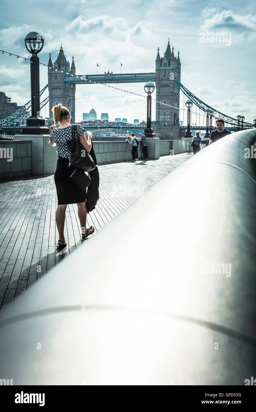 Eine junge Pendlerin, die auf dem Queen's Walk in der Nähe der Tower Bridge, London, England, Großbritannien, zur Arbeit geht Stockfoto