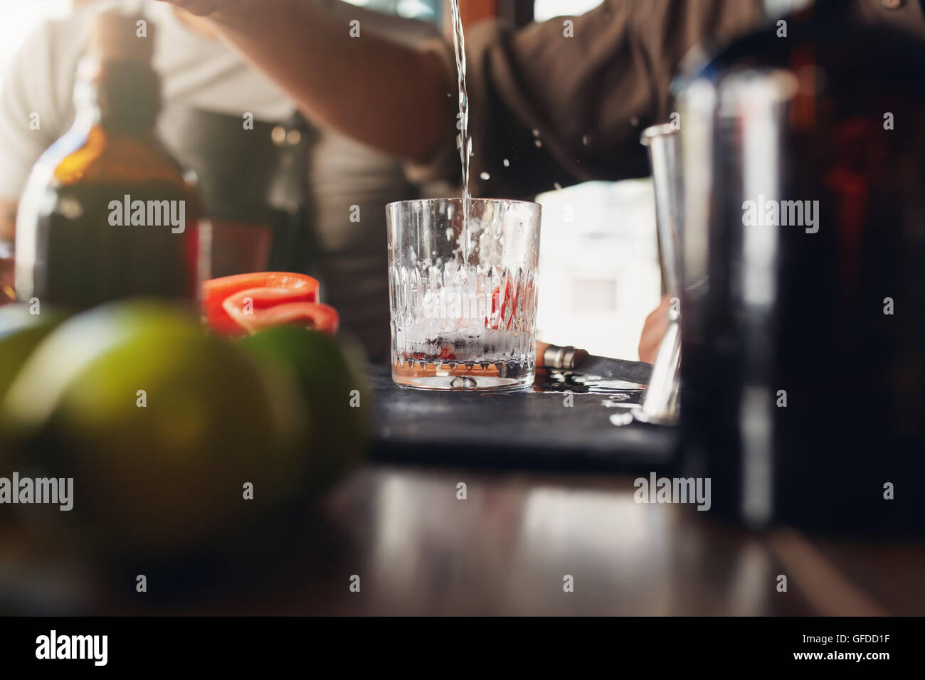 Closeup Aufnahme des Barkeeper Gießen Getränk in ein Glas auf der Theke. Vorbereitung Cocktail Barkeeper. Stockfoto