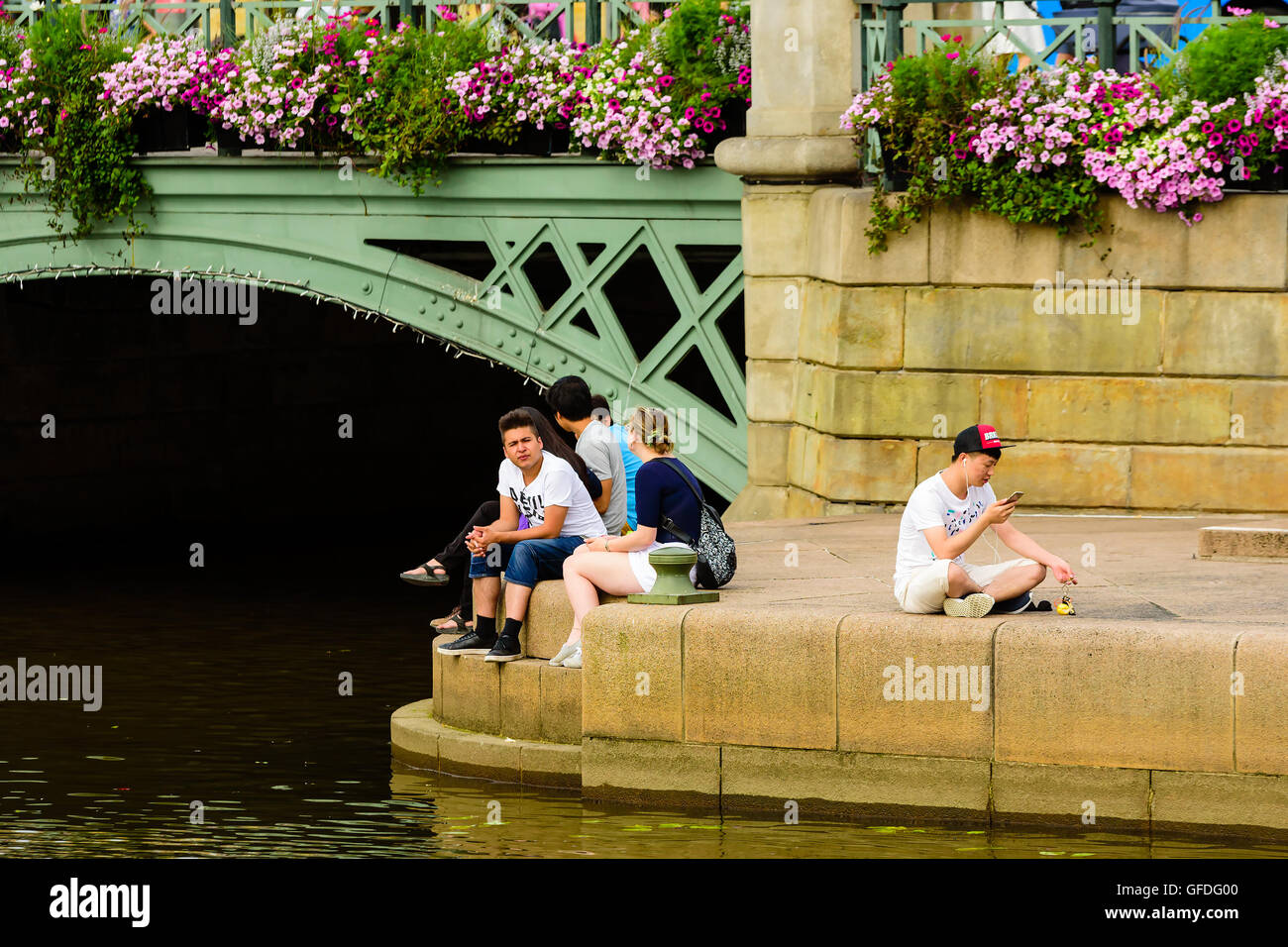 Göteborg, Schweden - 25. Juli 2016: Echte Menschen im Alltag. Junge Erwachsene Personen sitzen in der Nähe Wasser unter einer Brücke. Ein p Stockfoto