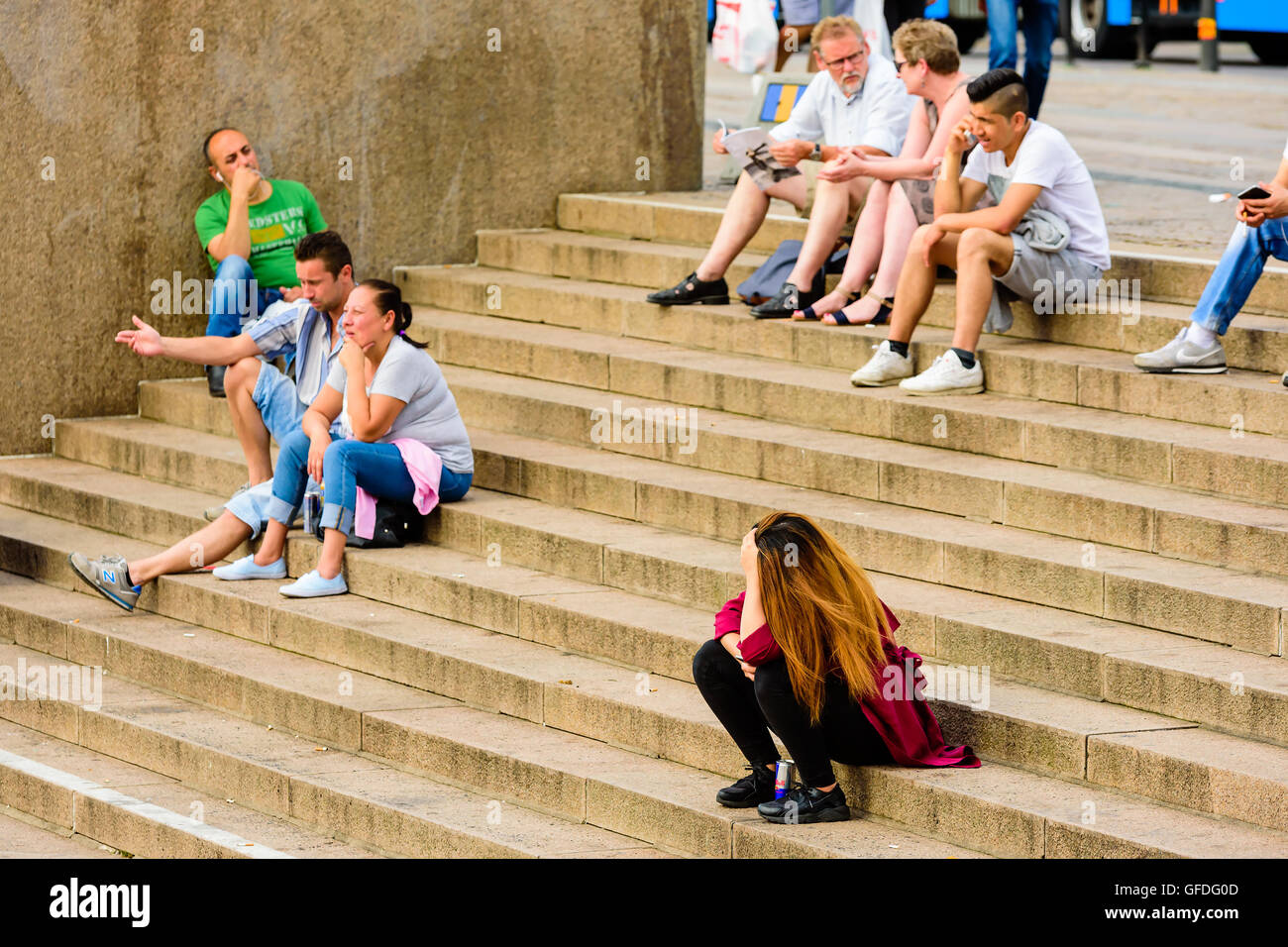 Göteborg, Schweden - 25. Juli 2016: Echte Menschen im Alltag. Junge Frau sitzt allein auf Steintreppen umgeben von gr Stockfoto