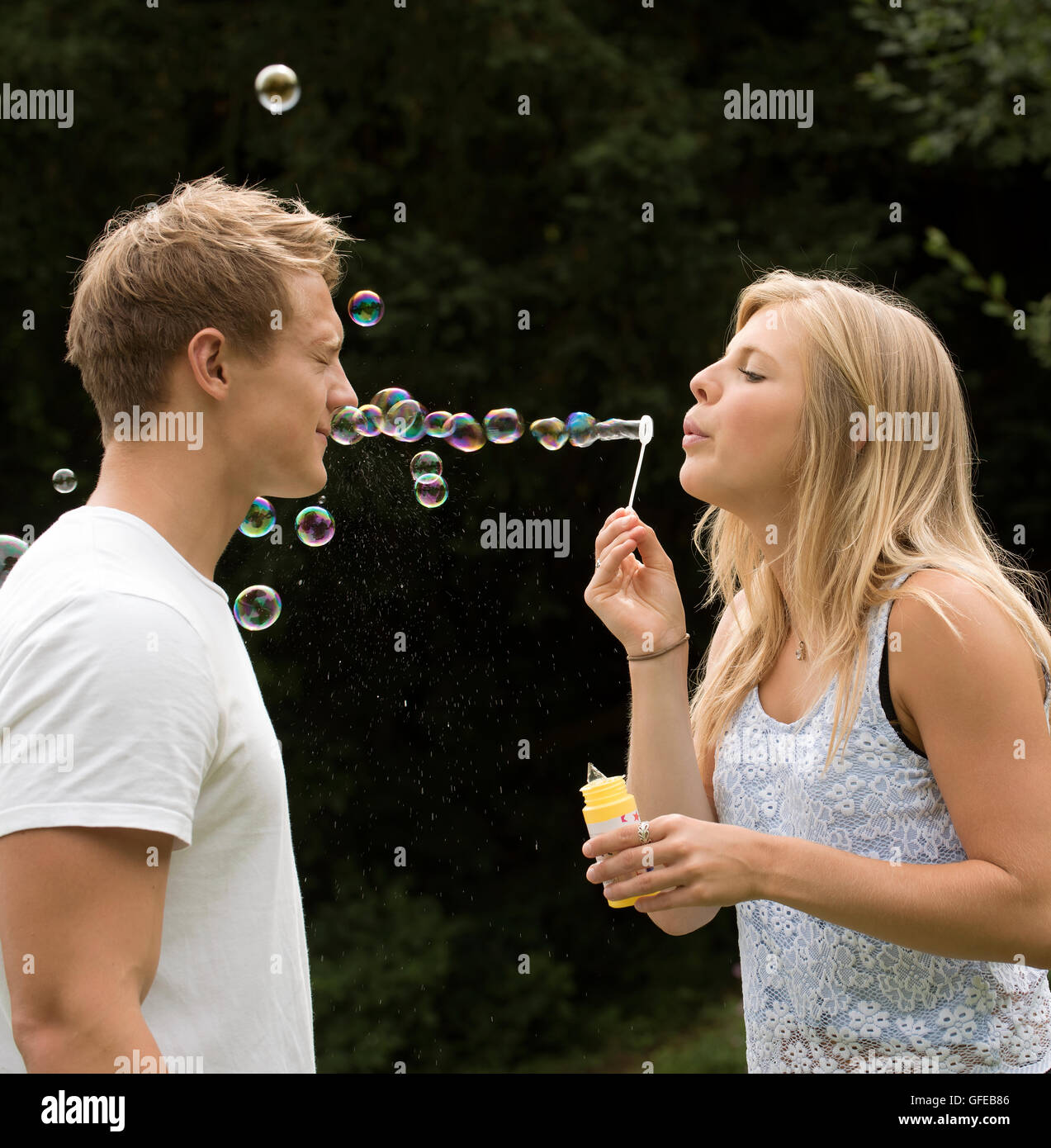TEENAGER BLOWING BUBBLES A teenage Girl bläst Seifenblasen bei ihrem Freund Stockfoto