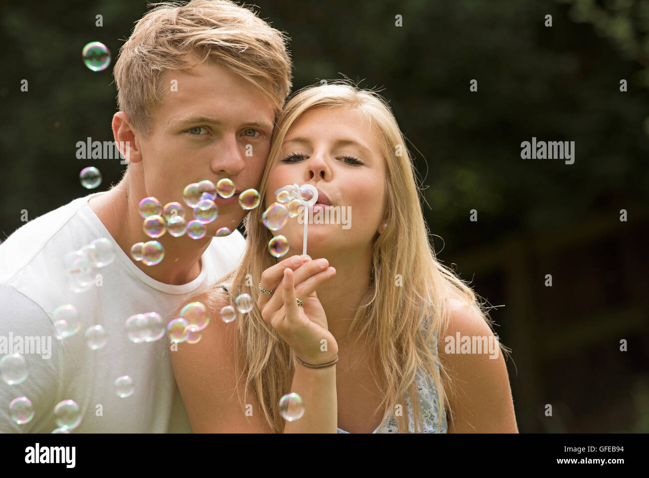 TEENAGER BLOWING BUBBLES A teenage Girl bläst Seifenblasen bei ihrem Freund Stockfoto