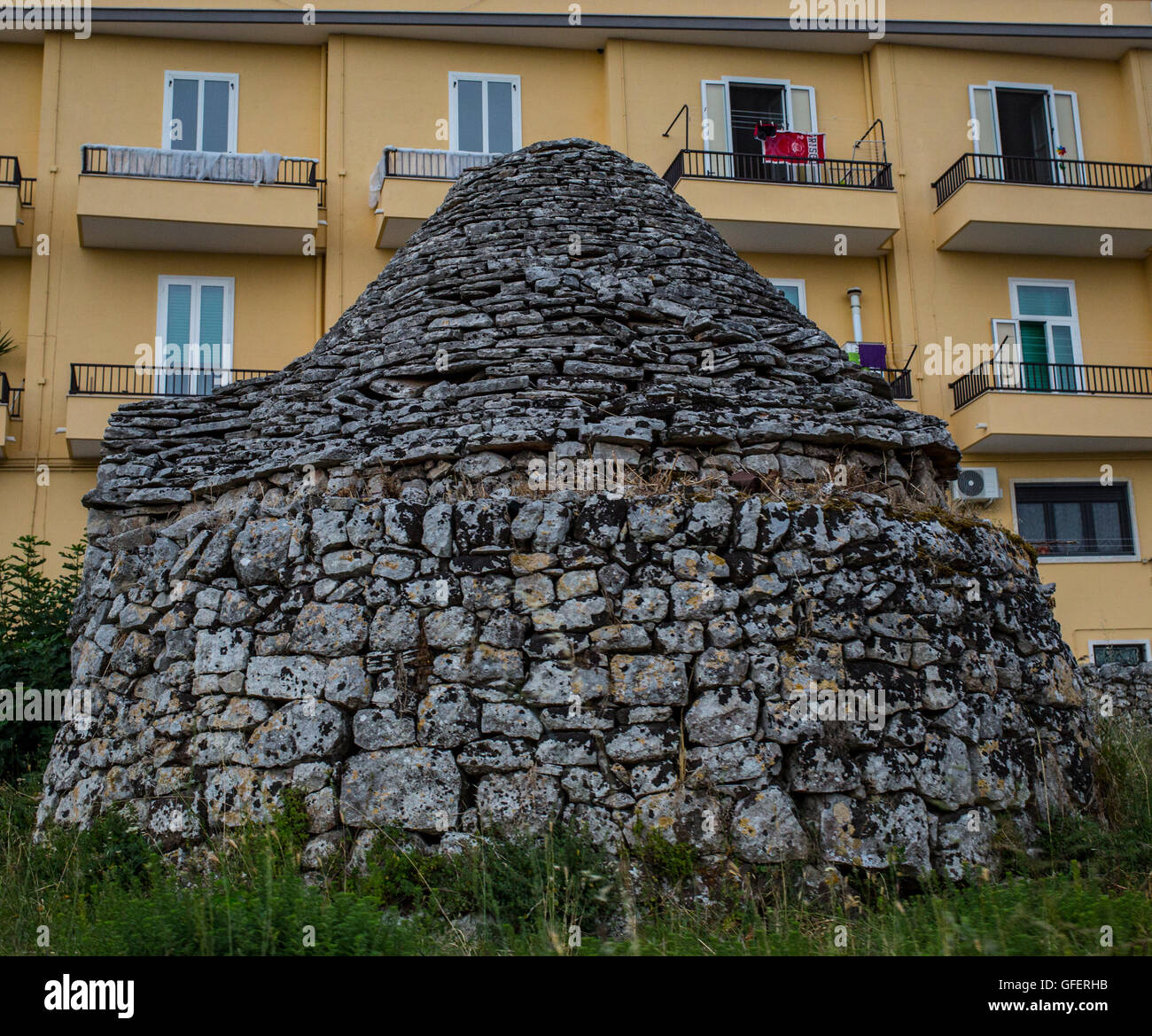 Ein traditionelles Trulli-Haus sieht man vor einem modernen Wohnblock in Martina Franca, Apulien, Italien Stockfoto