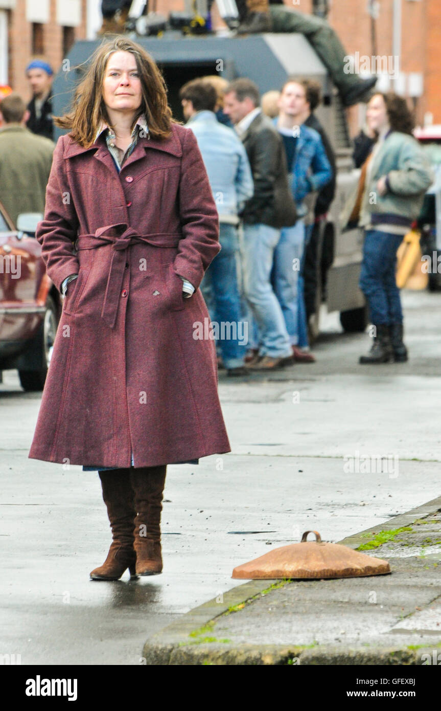 Belfast, Nordirland. 18. Dezember 2014 - steht eine Schauspielerin neben einem bin-Deckel Dreharbeiten eines Films in Belfast während the Troubles, bin-Deckel auf dem Boden als Warnung der Polizei oder Armee Tätigkeit im Bereich bang die Frauen weiter. Stockfoto