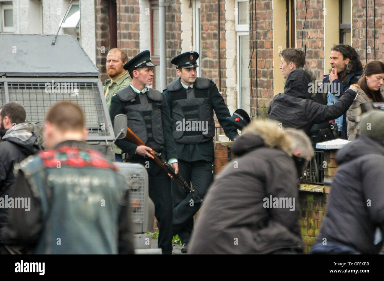 Belfast, Nordirland. 18. Dezember 2014 - verkleidet Akteure als Offiziere der Royal Ulster Constabulary (RUC) und irischen Republikanern Stand auf einer Straße in Belfast während eines Musik-Videos für U2s "Jede brechende Welle" zu schießen. Stockfoto