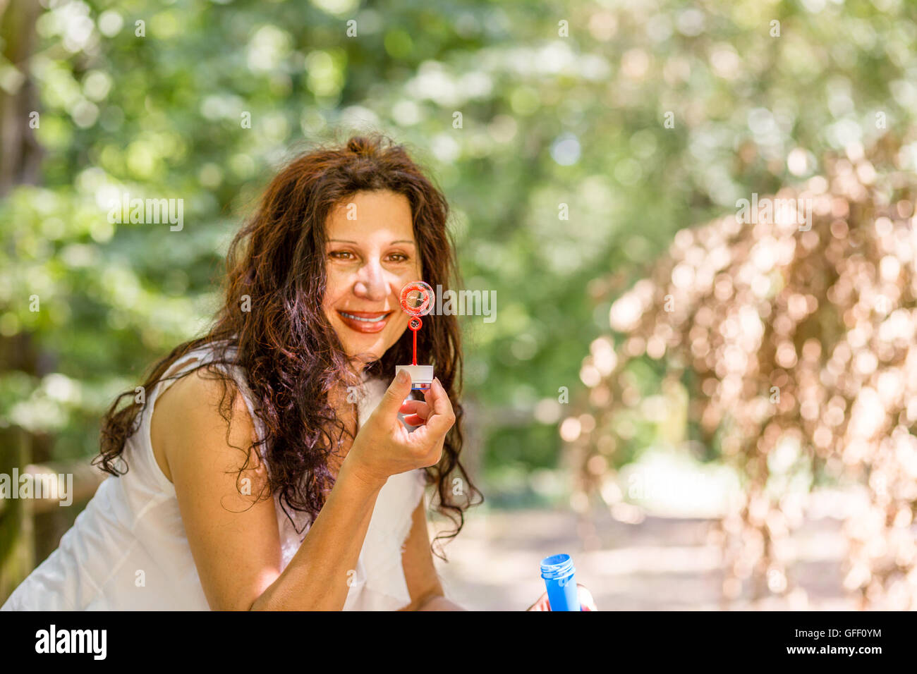 schöne Reife Dame hält eine Seifenblase mit Zauberstab und sah es Stockfoto