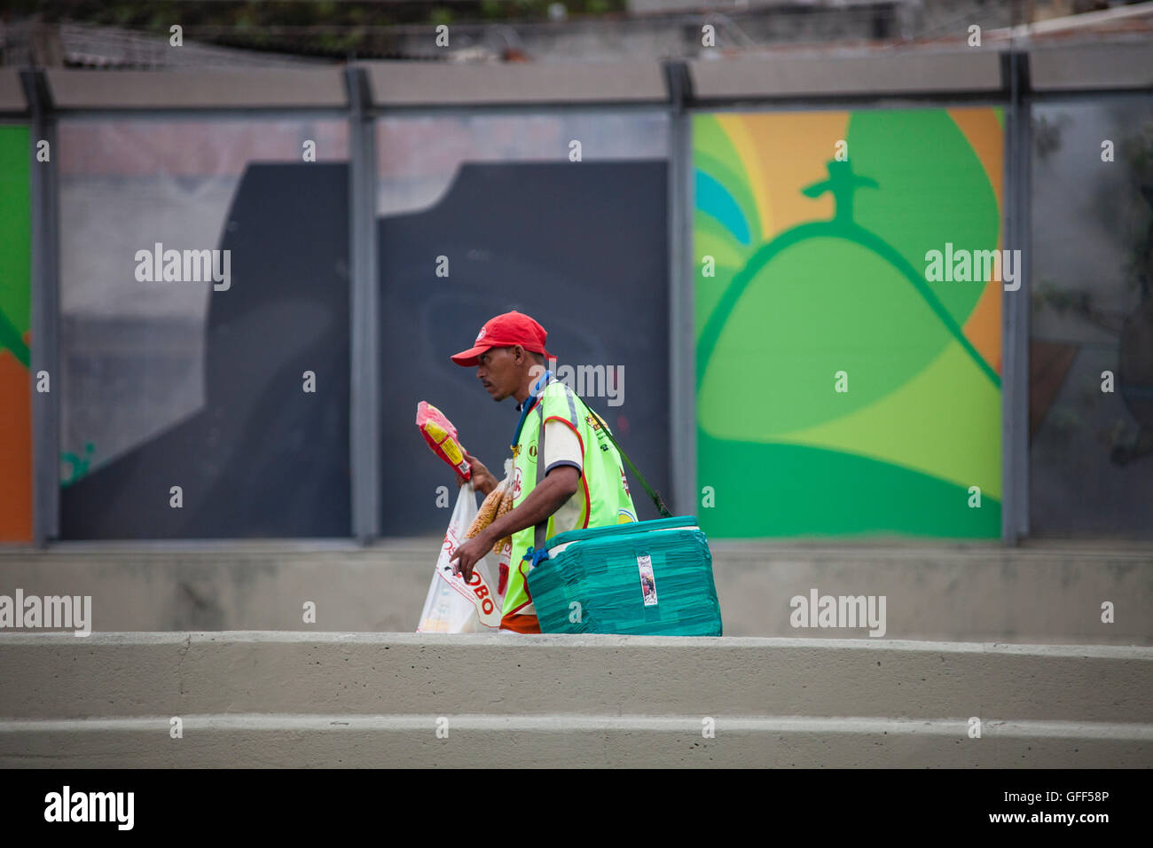 Bewohner von Complexo da Mare, einer massiven Netzwerk der Favelas, die neben der Linha Vermelha (rote Linie), die Autobahn vom Flughafen in die Innenstadt, Rio De Janeiro sitzt arbeiten als Straßenverkäufer während der Stoßzeiten an der Expreessway - seit 2010 ist die Gemeinschaft eingezäunten Weg von der Autobahn durch riesige Plexiglas Platten - Behörden behaupten sie bieten eine akustische Barriere , einheimischen beschreiben es als eine "Mauer der Schande", anders Arme Menschen zu verstecken. Stockfoto