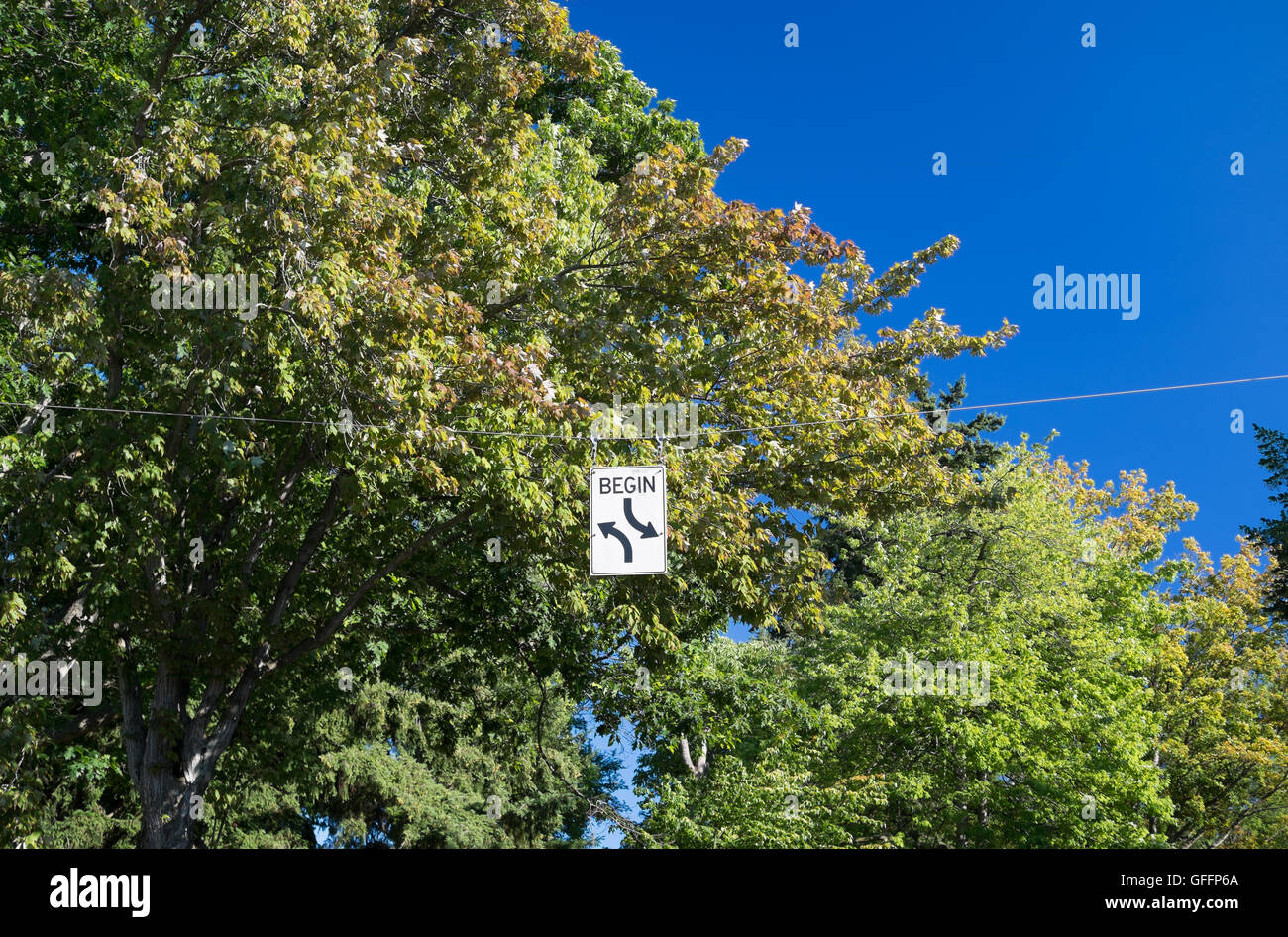 Begin zwei weg drehen Schild mit Bäumen und blauen Himmel Stockfoto
