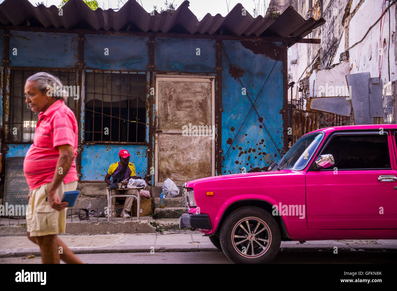 Havanna, Kuba am 23. Dezember 2015: ein Mann geht auf eine Straße in Centro Habana mit seinem Hemd Farbe von rosa Oldtim Stockfoto