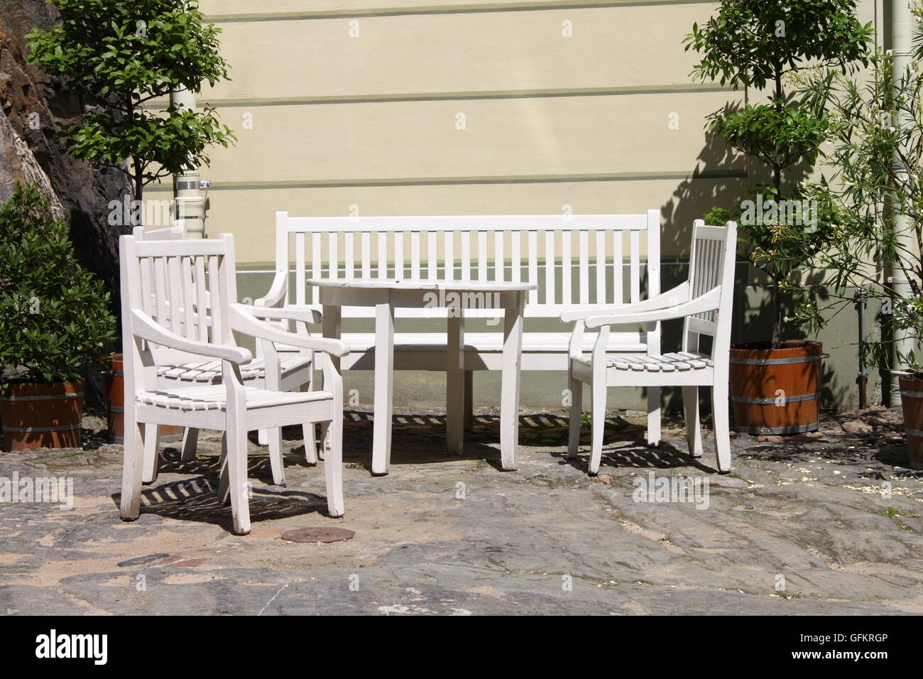 Weiß lackiertes hölzerne Patio-Möbel im Freien in einem befestigten Winkel eines Gartens Stockfoto