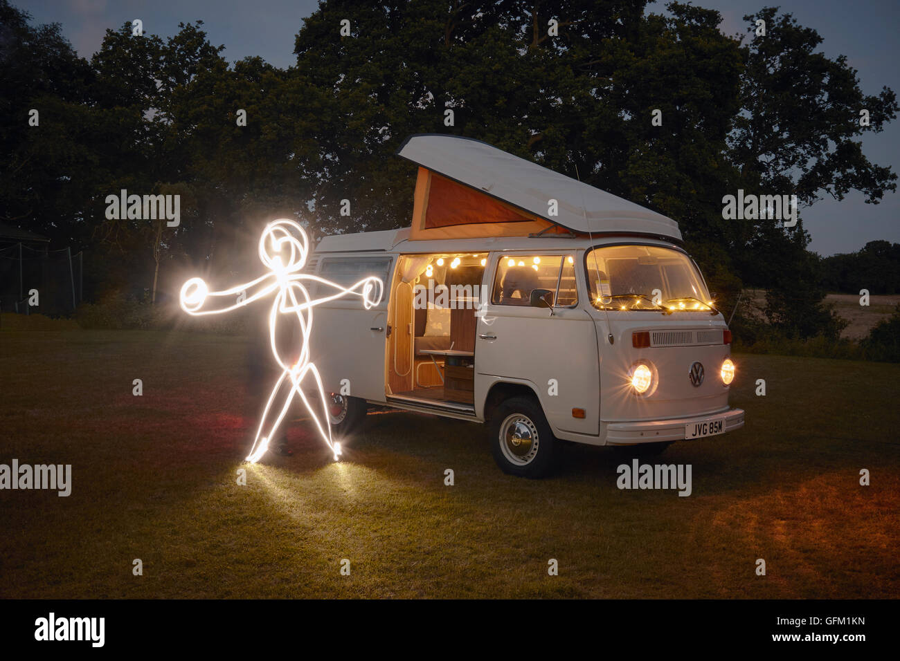 Eine leichte gemalte Figur neben einem VW Camper van. Stockfoto