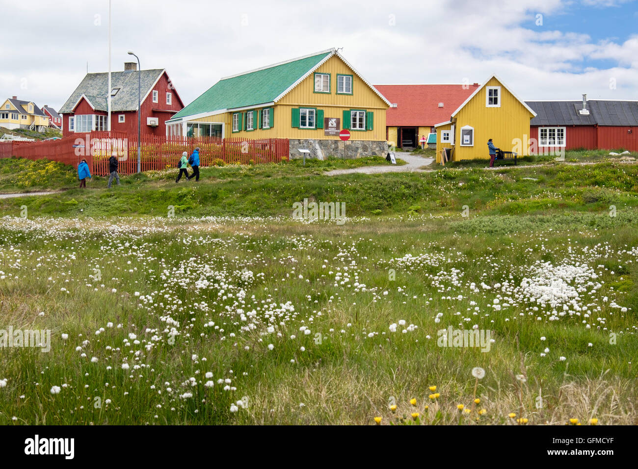 Touristen zu Fuß zum gelben Gebäude im Sommer. Paamiut (Frederikshåb), Sermersooq, Grönland Stockfoto