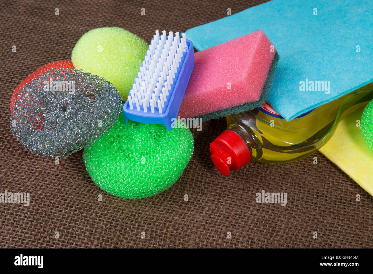 Behälter mit Flüssigkeit für Glas, Tücher, bunte Schwämme zum Waschen, blaue Reinigungsbürste Stockfoto