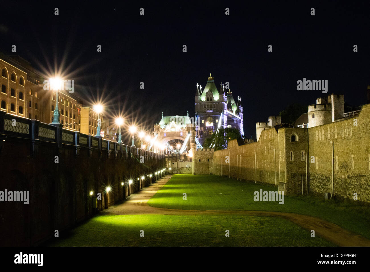 Bild der Innenhof mit der Tower Bridge in London im Hintergrund in der Nacht mit einer Reihe von Lampe Beiträge berücksichtigt neben Stockfoto