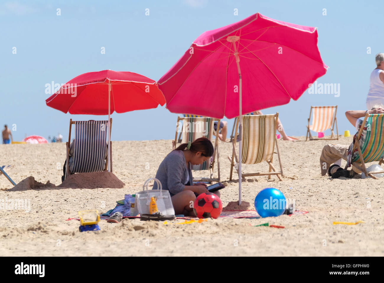 Frau im Schatten der Sonnenschirm am Strand von Great Yarmouth Stockfoto
