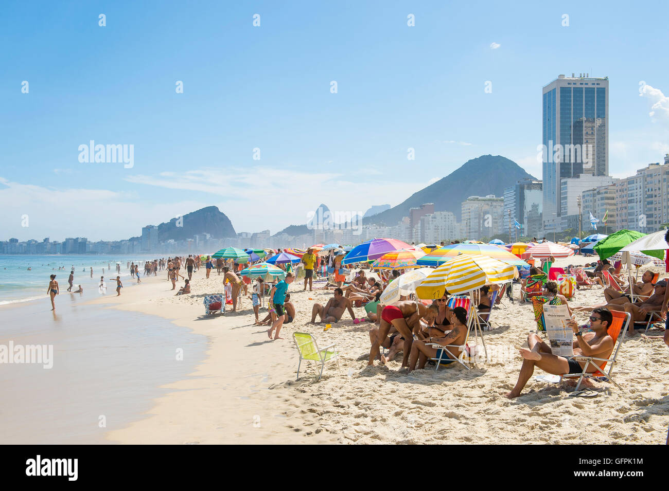 RIO DE JANEIRO - 27. Februar 2016: Massen der Strandbesucher füllen Copacabana-Strand mit bunten Sonnenschirmen am hellen Nachmittag. Stockfoto