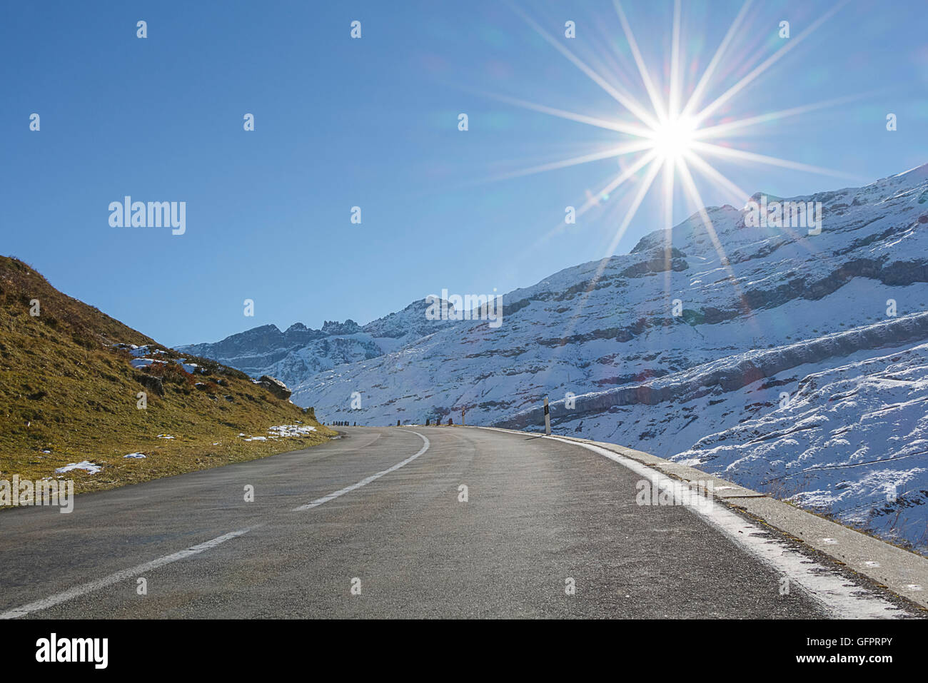 Ein Berg Straße mit der Sonne direkt voraus. Ließe sich treibende Urlaub oder Abenteuer zeigen Stockfoto
